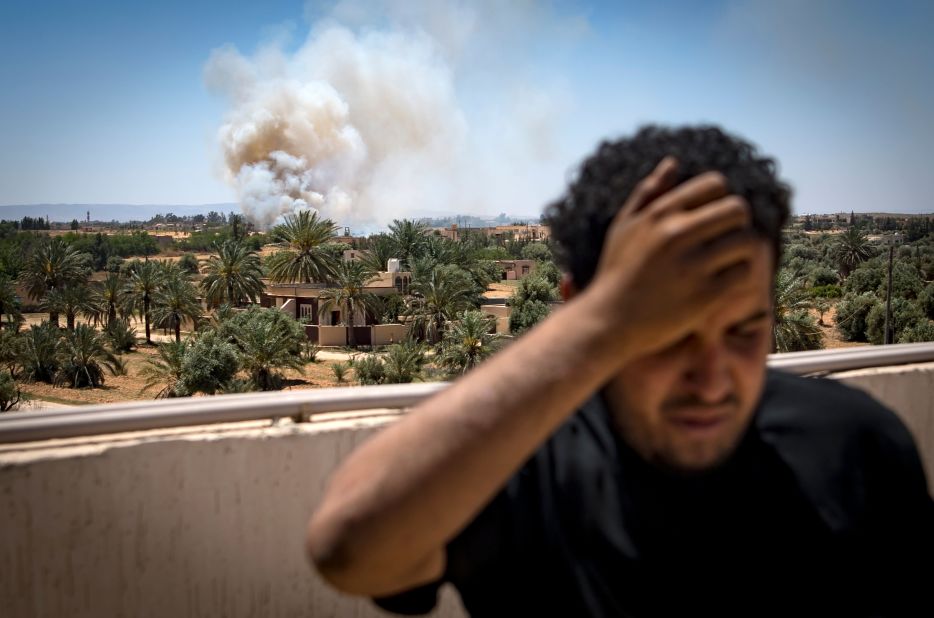 A fighter loyal to the Government of National Accord stands on a rooftop as smoke rises in the distance on April 29.