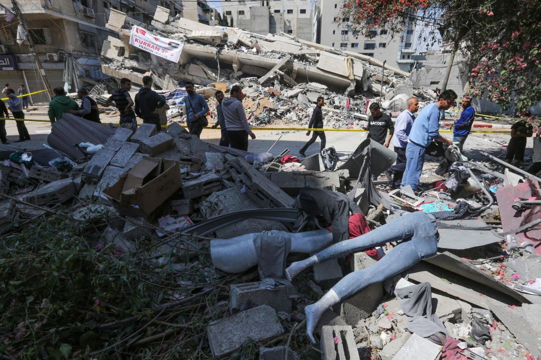 Palestinians walk by a clothing shop damaged by Israeli airstrikes on Saturday. 