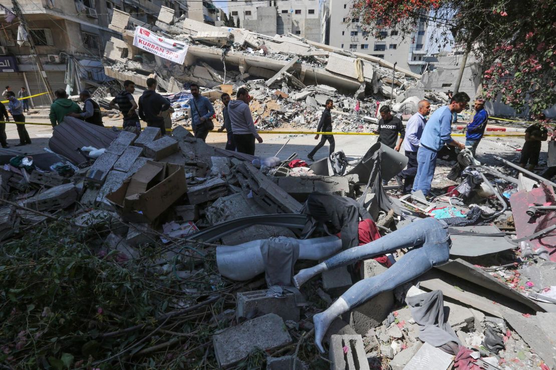 Palestinians walk by a clothing shop damaged by Israeli airstrikes on Saturday.