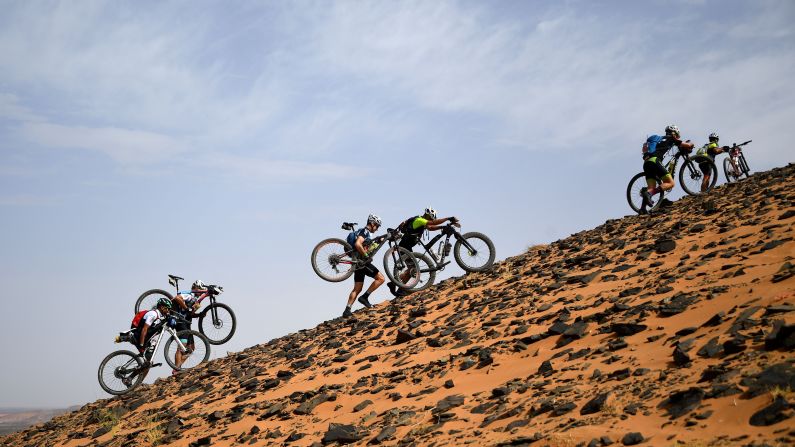 Competitors carry their bicycles along a sand dune during Stage 2 of the 14th edition of Titan Desert 2019 mountain biking race between Merzouga and Ouzina in Morocco on Monday, April 29.