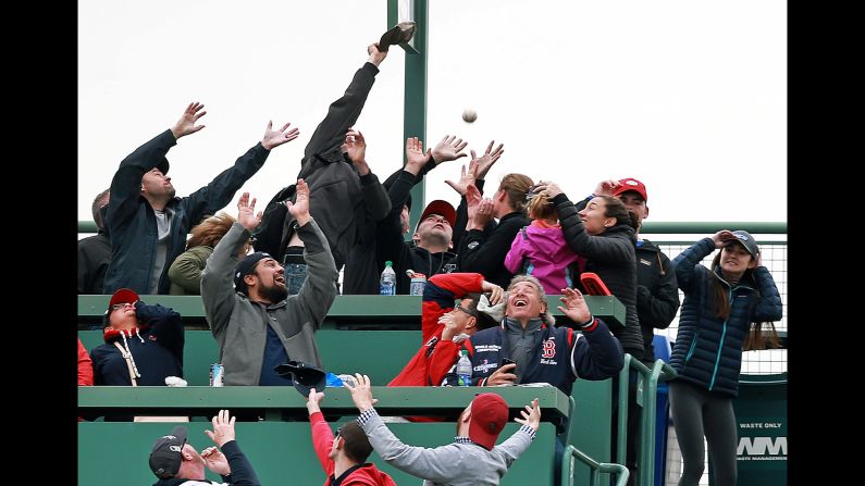 Fans seated in the Green Monster seats attempt to catch a home run ball hit by Red Sox player Christian Vazquez during the bottom of the eighth inning of a game against the Oakland Athletics at Fenway Park on May 1 in Boston.