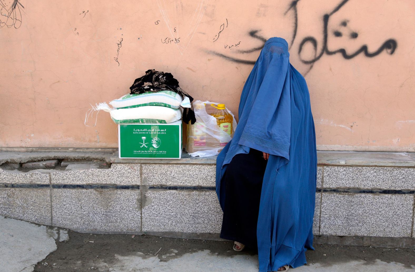 An Afghan woman receives free food donated by King Salman Humanitarian Aid and Relief Center, ahead of the upcoming holy fasting month of Ramadan in Kabul, Afghanistan, Sunday, May 5. 