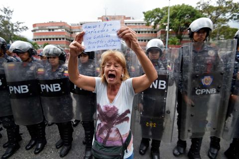 A woman demonstrates in front of police outside the Venezuelan navy headquarters in Caracas on Saturday, May 4.