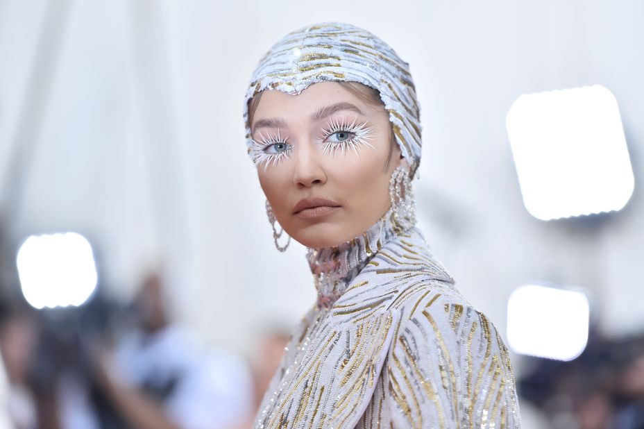 Supermodel Gigi Hadid walked into the Met Gala on the arm of American fashion designer Michael Kors, wearing a metallic form-fitting catsuit with matching feather cape and headpiece. She accessorized with rose-cut diamond earrings by Lorraine Schwartz, contributing to a total of nearly 90 carats of diamonds.
