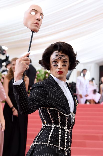 Ezra Miller arrived on the red carpet wearing a Burberry-designed outfit, which included a white dress shirt and a mask. But all eyes were on Miller, as he removed the mask to reveal a seven-eyed look paired with a black pinstriped suit and an overlaid crystal-studded corset.