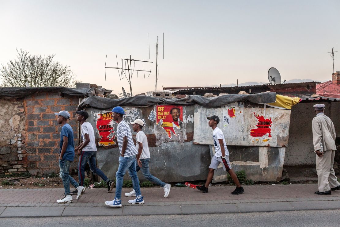 People walk past posters for the South African opposition political party, Economic Freedom Fighters (EFF) in the run up to elections.