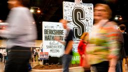 People walk past signs welcoming them to the annual Berkshire Hathaway shareholders meeting in Omaha, Neb., Friday, May 3, 2019. On Saturday estimated 40,000 people are expected in town for the event, where Chairman and CEO Warren Buffett and Vice Chairman Charlie Munger will preside over the meeting and spend hours answering questions. (AP Photo/Nati Harnik)