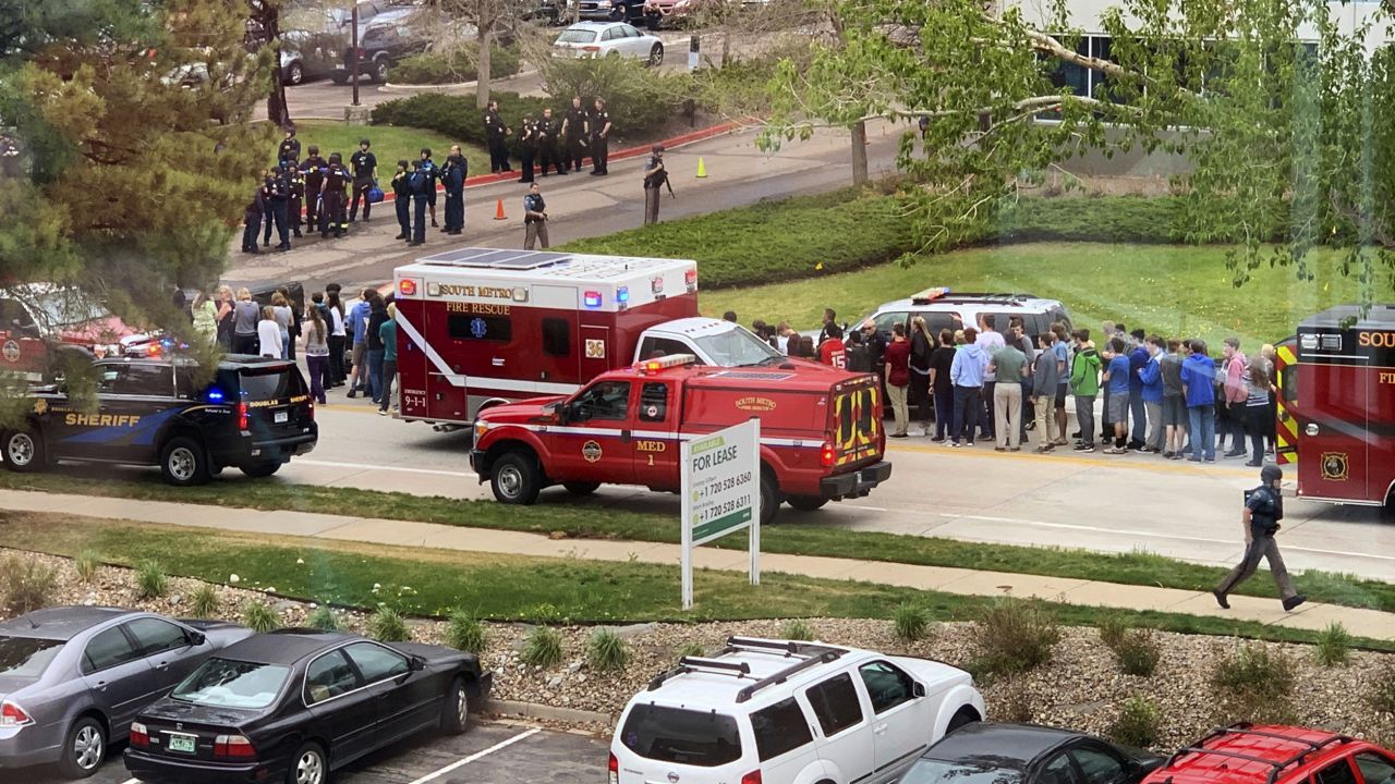 Police officers and students are seen outside STEM School Highlands Ranch, a charter middle school in the Denver suburb of Highlands Ranch, Colo., after a shooting Tuesday, May 7, 2019. (Courtney Harper via AP)