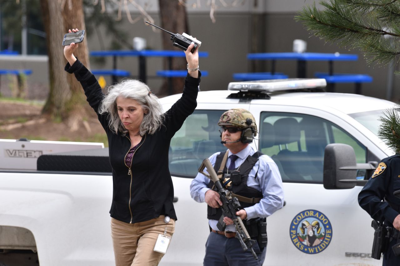 A teacher raises her arms as she exits the scene of the shooting at the STEM School Highlands Ranch.