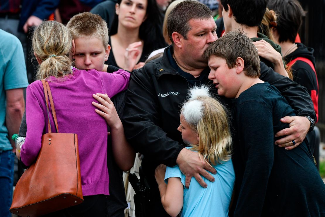 A police officer hugs his kids after they were evacuated to the Recreation Center at Northridge.