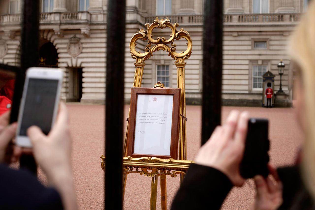 People take pictures of a notice, posted outside Buckingham Palace, that announced the baby's birth.