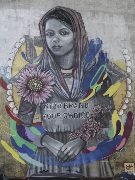 This mural represents the problem of child labor in the fashion industry in Bangladesh. It tells the story of Bithi, who says she was sent to work in a factory at the age of 12, helping to make designer jeans. According to World Vision, who provided her account to SAM, she helped to make 480 pairs of jeans a day, for which she was paid just over $1. The mural on 28 Cliff Street was painted by Mexican street artist KinMx.