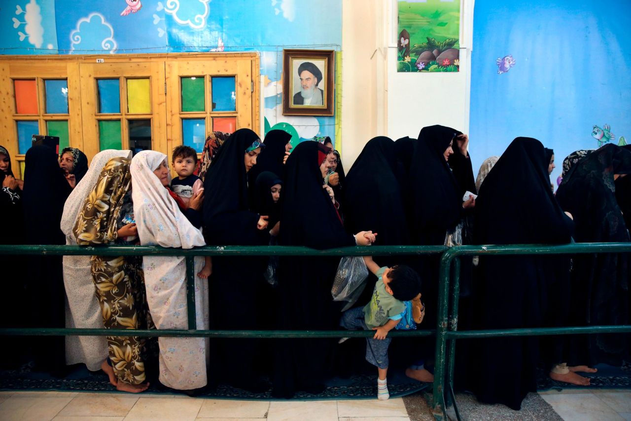 Under a portrait of the late Iranian revolutionary founder Ayatollah Khomeini, pilgrims line up for the Iftar meal to break their fast at sunset in Shahr-e-Ray, south of Tehran, Iran, on Wednesday.