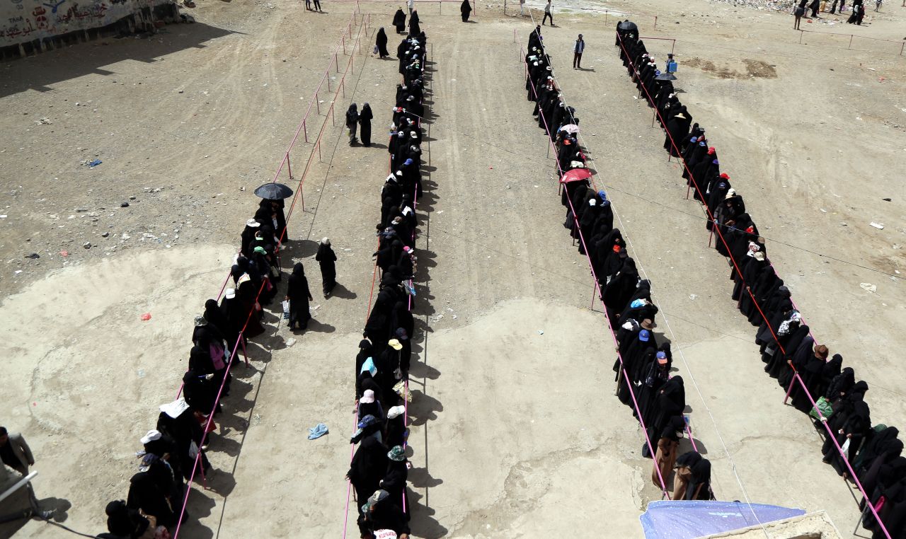 Yemeni women from families, who were affected by the ongoing war, line up to receive dinner from a charity organization.