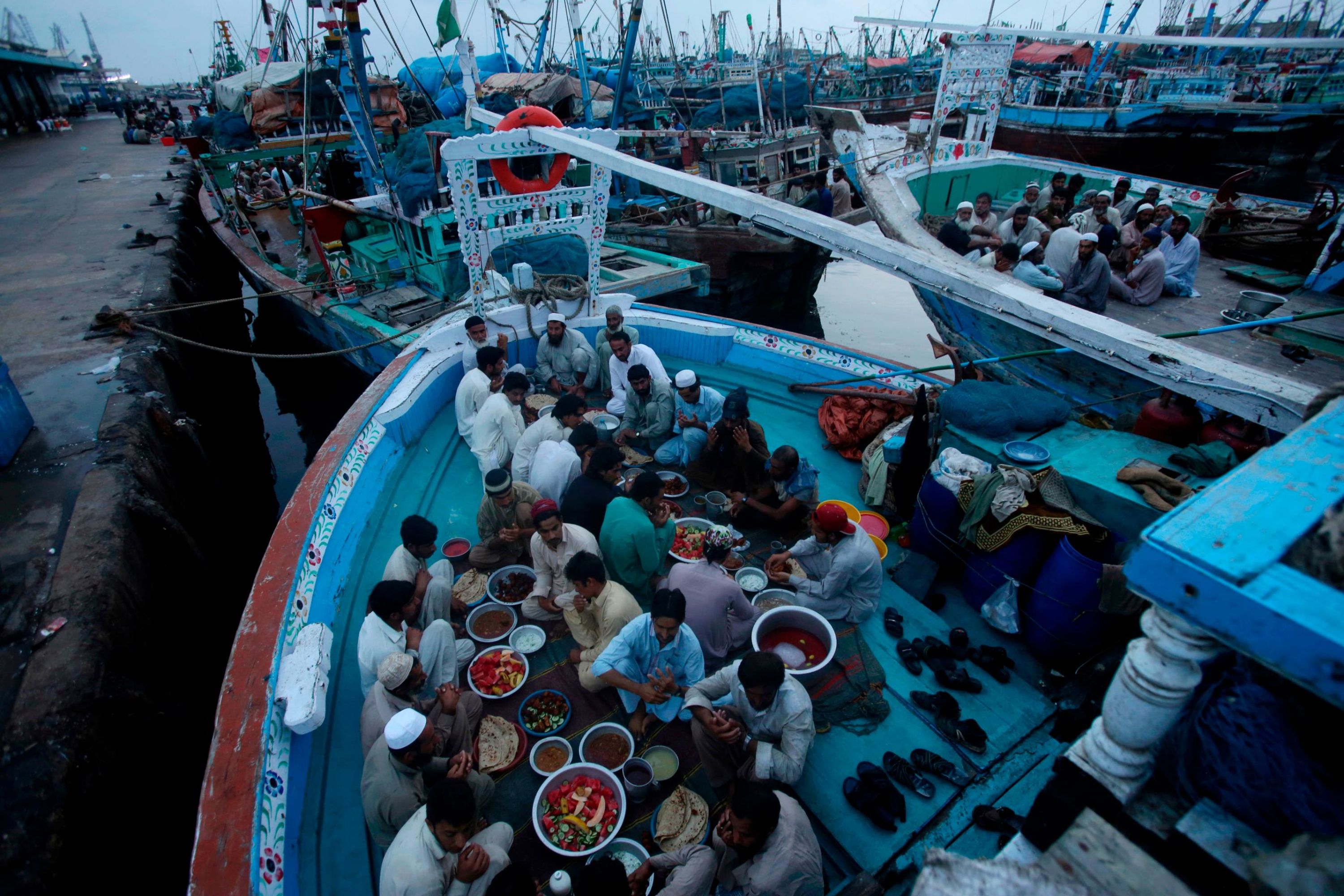 Pakistani fishermen sitting in their boats, pray before breaking their fast in Karachi on Thursday.