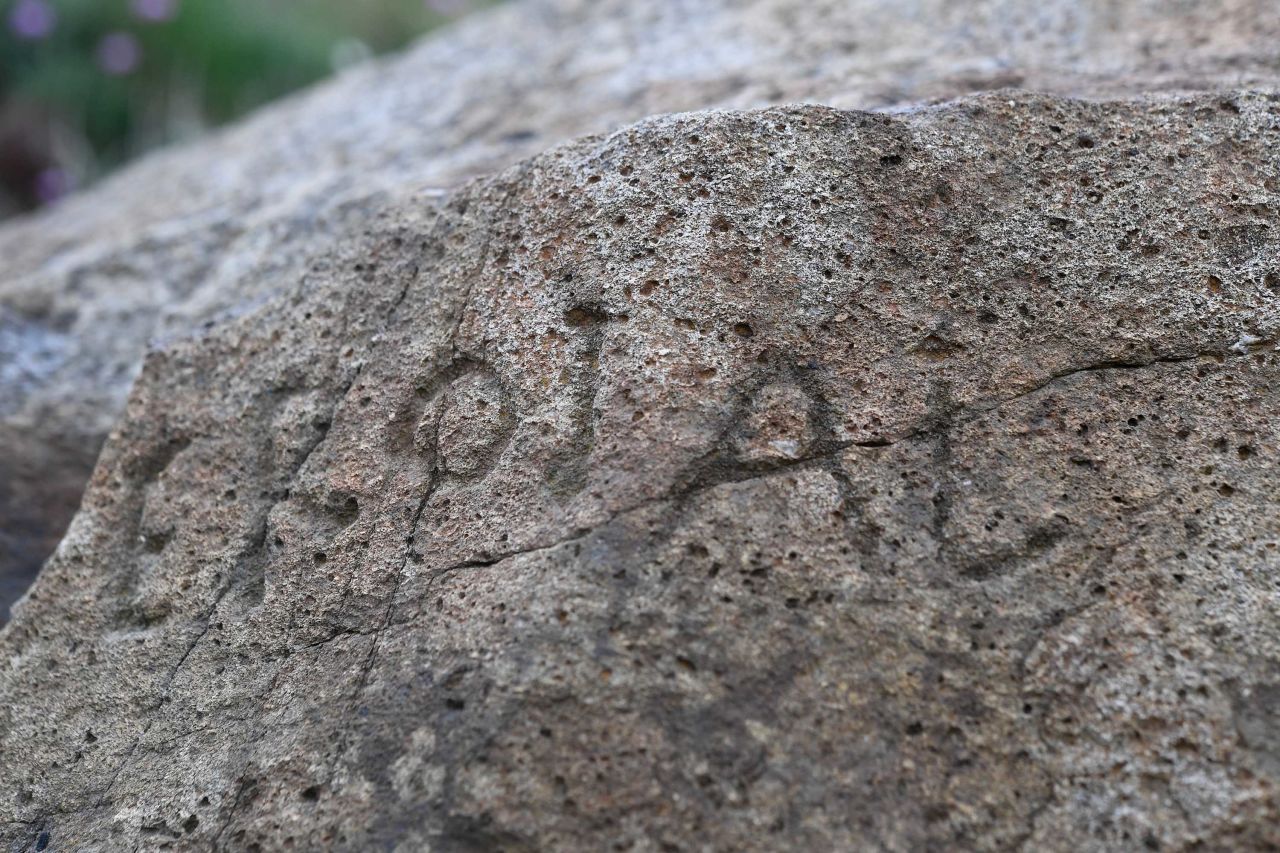 There are letters, symbols and dates etched into the rock.