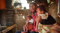 Hajja Ibrahim holds her son and her daughter inside their hut in the village of Bani Qais.