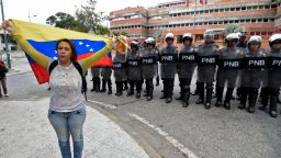 A woman demonstrates with a Venezuelan national flag, in front of a line of riot police outside the Venezuelan Navy command headquarters at San Bernardino neighborhood in Caracas on May 4, 2019. - Venezuelan President Nicolas Maduro called on the armed forces to be "ready" in the event of a US military offensive against the South American country, in a speech to troops on Saturday. His speech at a military base came as opposition leader Juan Guaido rallied his supporters in a new day of protests to press the armed forces to support his bid to dislodge Maduro. (Photo by Juan BARRETO / AFP)        (Photo credit should read JUAN BARRETO/AFP/Getty Images)