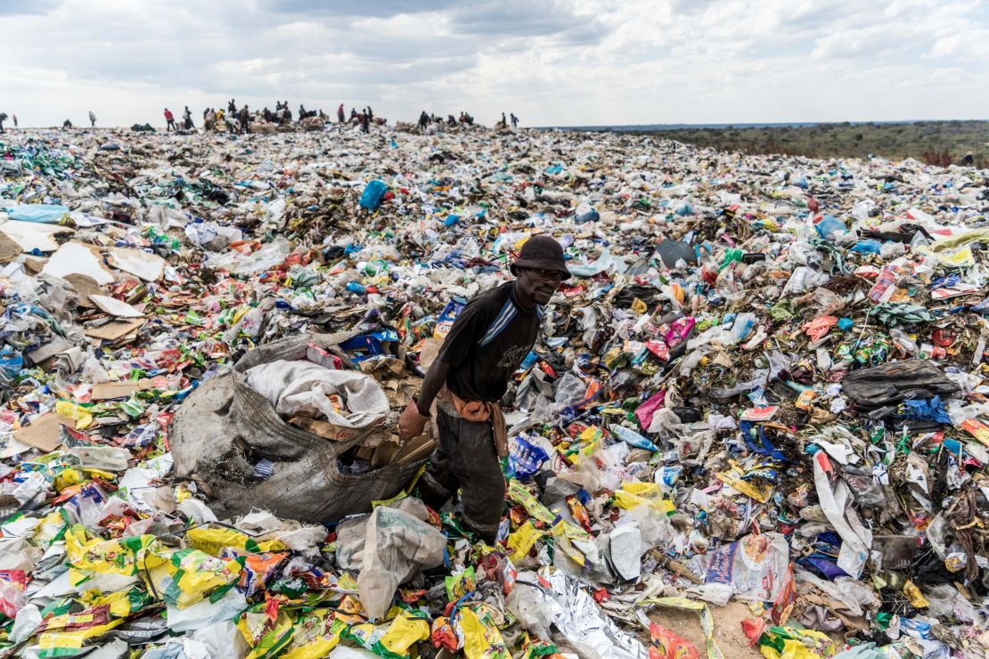 A recycler drags a huge bag of paper through a heap of non-recyclable waste in Zimbabwe.