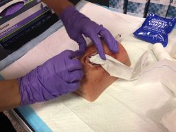 An attendee of the Stop the Bleed class uses a dummy to practice packing a wound with gauze. 