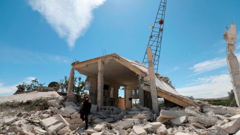 A Syrian Civil Defense member inspects the rubble following shelling in the village of Maarit Sin Saturday.