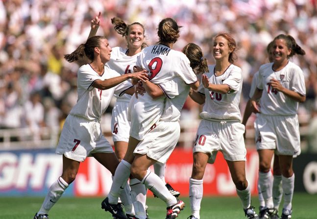 Mia Hamm (9) is embraced by Shannon MacMillan (8) as teammates Joy Fawcett, Kate Sobrero, Carla Overbeck and Sara Whalen celebrate victory. Carla Overbeck, Fawcett, Kristine Lilly and Hamm all converted their spot-kicks. 