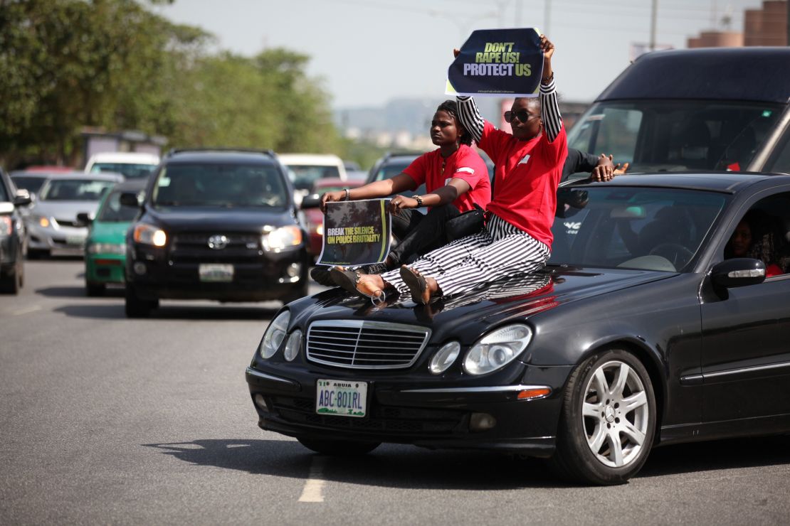Two women display their placards as they sit on a car during one of the protest in Abuja on May 10. 