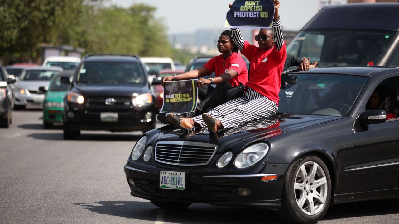 Two women display their placards as they sit on a car during one of the protest in Abuja on May 10.