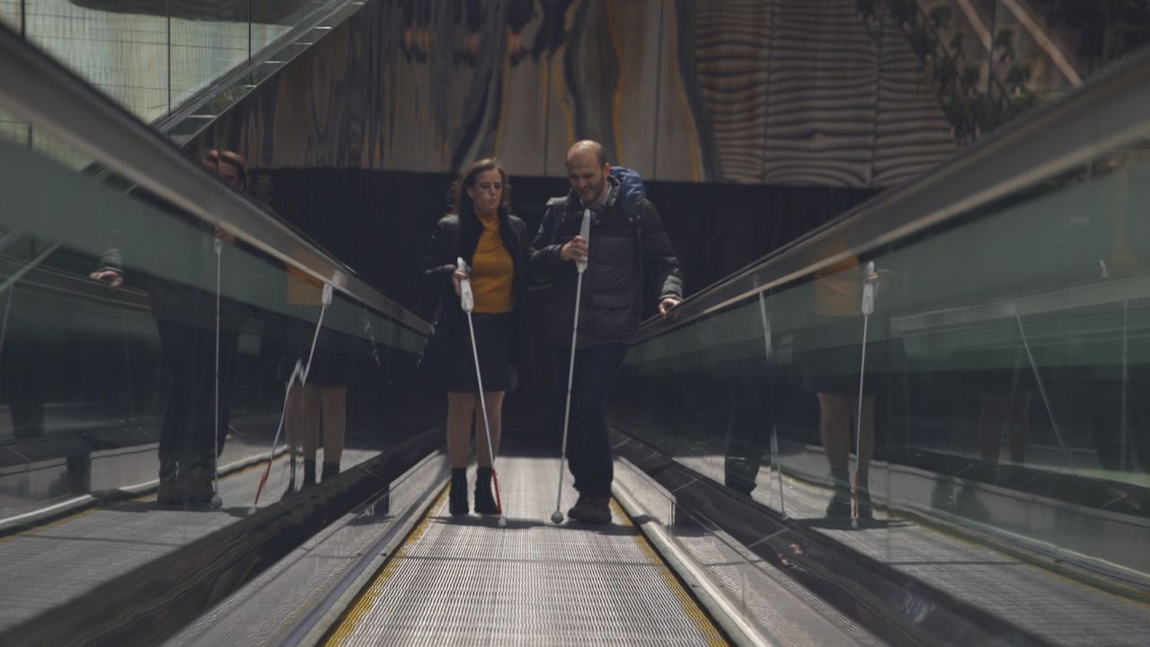 Kursat Ceylan (right) uses the WeWalk smart stick on his way to work