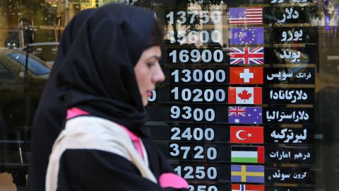 An Iranian woman walks past a currency exchange shop in the capital Tehran, Iranians, where locals are hard hit by punishing US economic sanctions