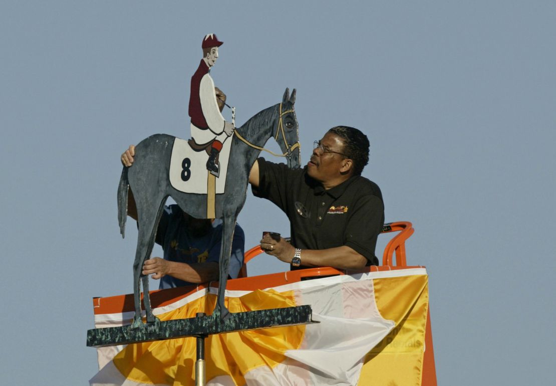 An artist paints the winning colors on the weather vane at Pimlico Race Track after the Preakness Stakes.