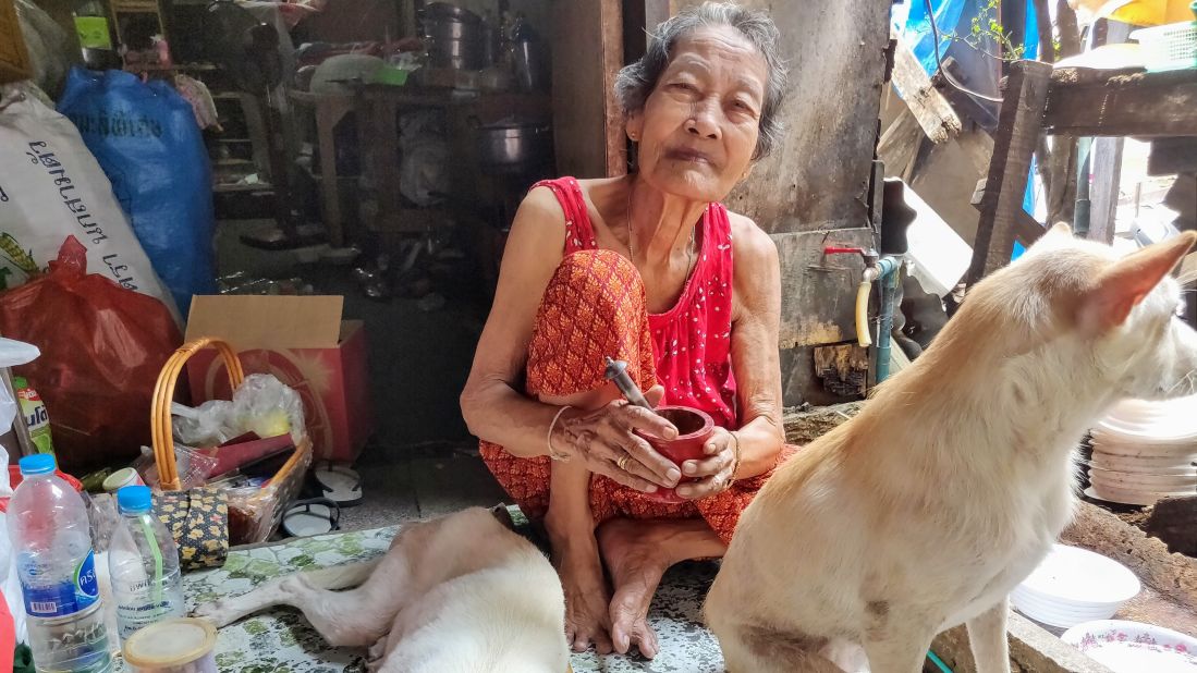 Accompanied by her loyal canine companions, this lady is grinding fresh betel nuts. Young Thais don't chew betel but the habit <a href="https://www.ncbi.nlm.nih.gov/books/NBK304393/" target="_blank" target="_blank">still persists among some elderly people</a>.