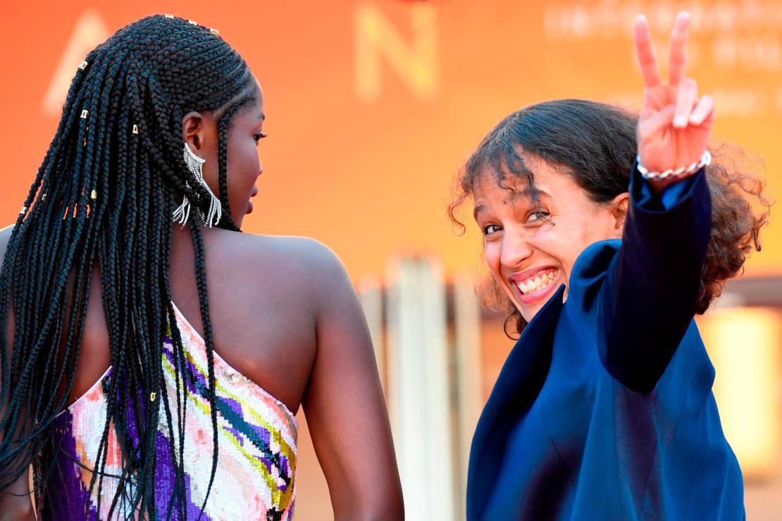 Mati Diop flashes a victory sign as she arrives with Senegalese actress Mama Sane for the gala screening of "Atlantics" at the 72nd Cannes Film Festival.