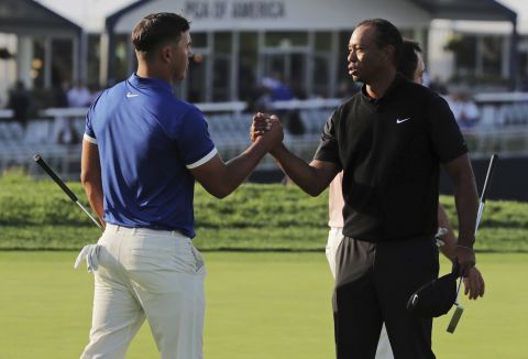 Brooks Koepka, left, shakes hands with Tiger Woods after finishing the second round.