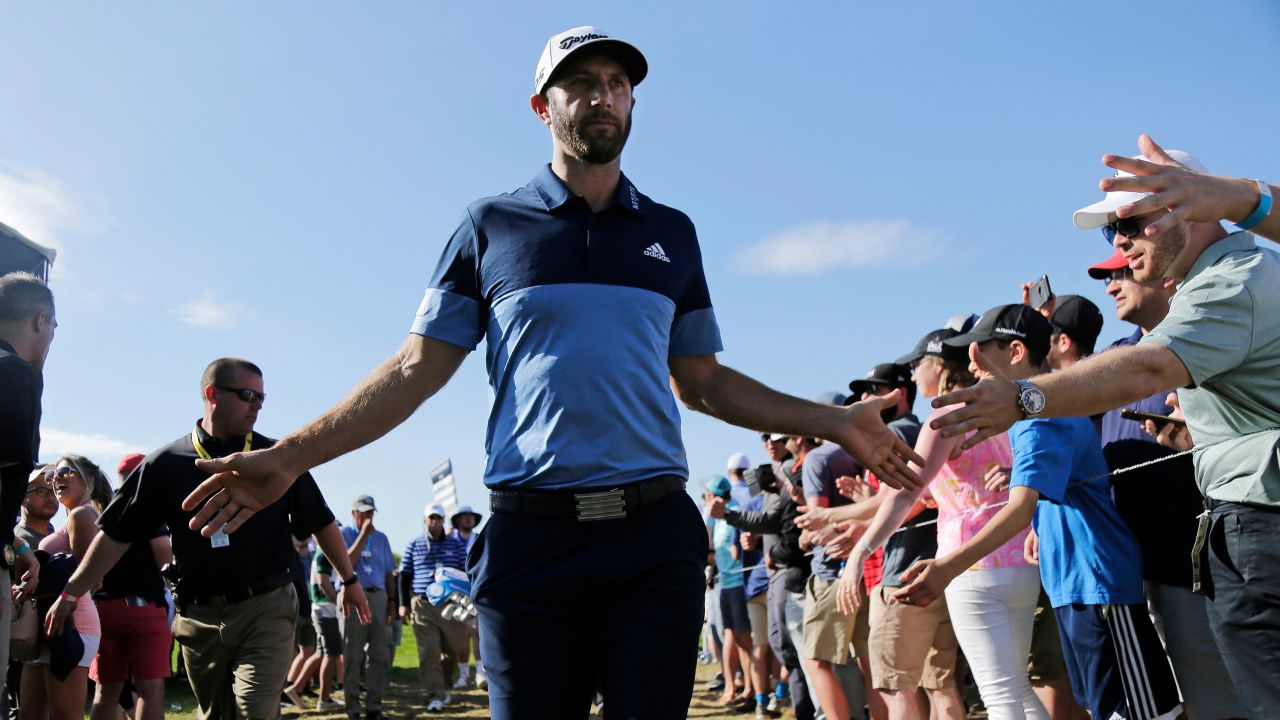 Dustin Johnson greets spectators as he walks to the 12th tee.