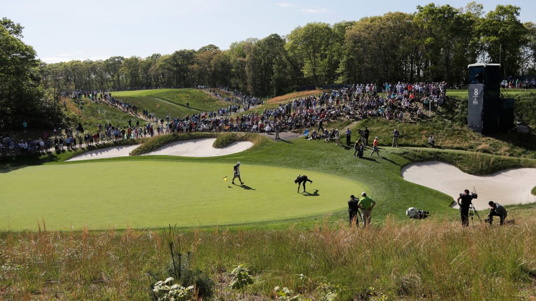 Brooks Koepka picks his ball out of the hole after putting on the eighth green.