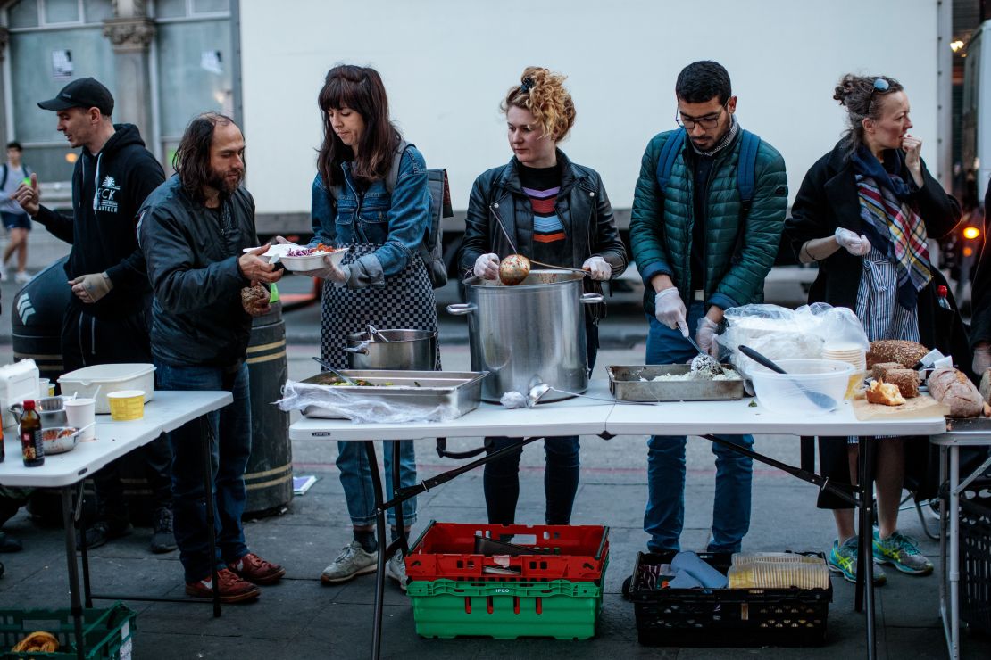 A free hot meal is served by volunteers from Refugee Community Kitchen to people outside Camden Town Underground Station on April 17 in London, England. 