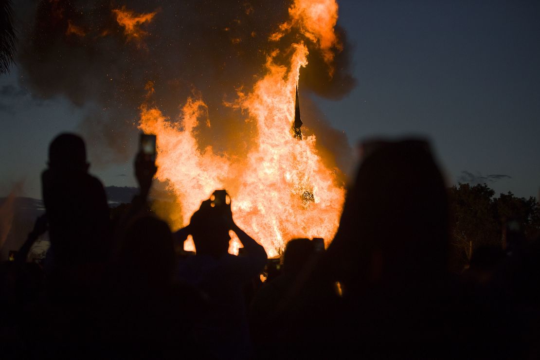 People watch as a temporary art installation burns in Coral Springs, Florida. 