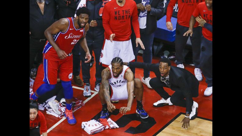 Philadelphia 76ers center Joel Embiid, left, and Toronto Raptors guard Jordan Loyd, right, look on as Kawhi Leonard, center, waits for his last-second shot to drop through the hoop during Game 7 of the NBA Eastern Conference Semi-finals on Sunday, May 12 in Toronto. <a href="index.php?page=&url=https%3A%2F%2Fbleacherreport.com%2Farticles%2F2835918-video-kawhi-leonards-epic-game-7-buzzer-beater-bounces-4-times-drops-for-win" target="_blank" target="_blank">The shot</a> bounced on the rim four times before finally falling through the bottom of the net to clinch the victory for Toronto. 