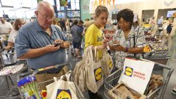Lidl employee Jessica Donna, center, helps shoppers with the Lidl app during the grand opening of one of the first Lidl grocery stores in the United States, Thursday, June 15, 2017, in Virginia Beach, Va. Several Lidl stores opened across the nation on Thursday. (AP Photo/Steve Helber)