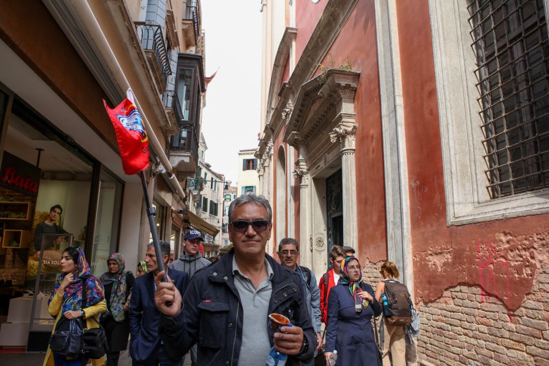 A tour guide leads his group through Venice's winding streets. 