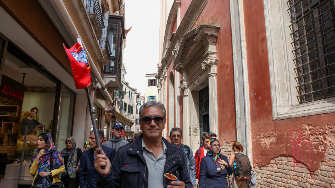A tour guide leads his group through Venice's winding streets. 