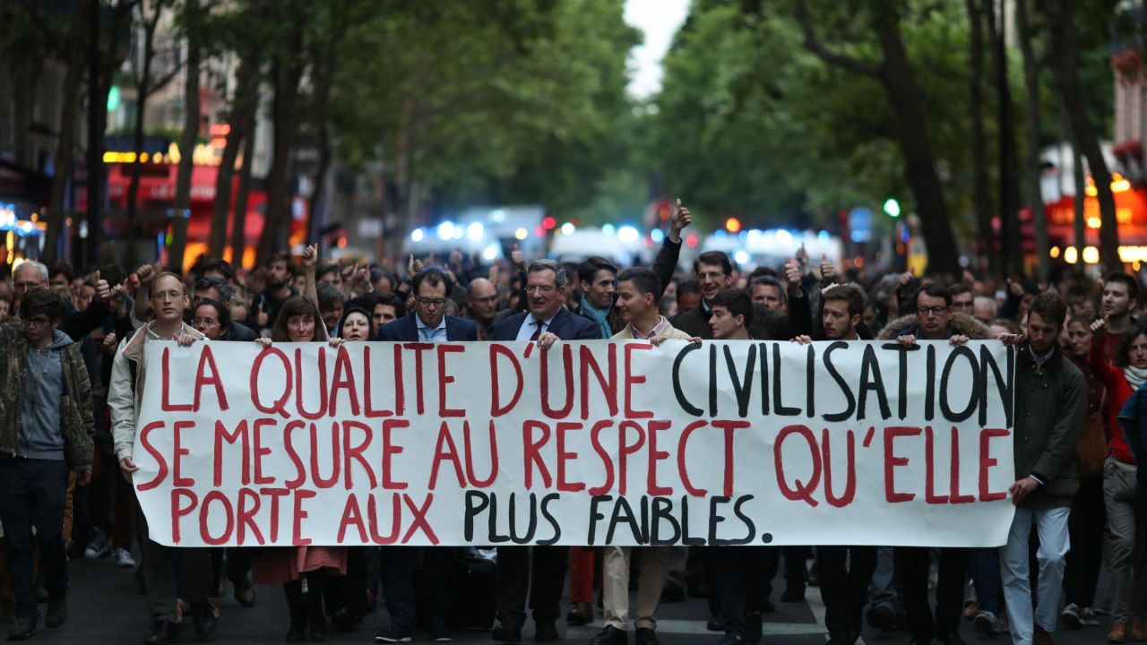 Protesters hold a sign reading "the quality of a civilization is measured by the respect it gives to the weakest" on Monday.