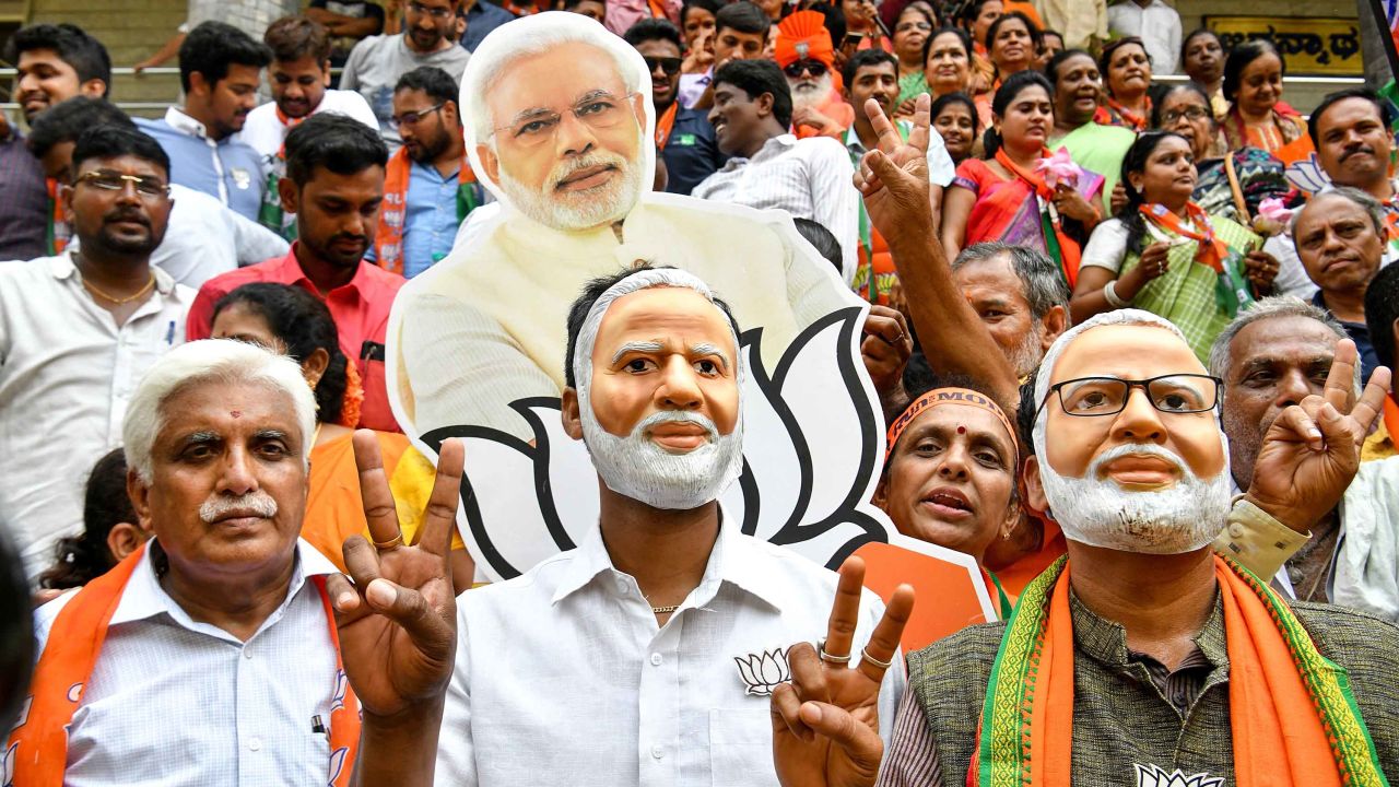Supporters wear masks of Indian Prime Minister Narendra Modi and flash victory signs as they celebrate on the vote results day for India's general election on May 23, 2019. 