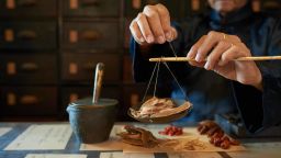 Man measuring ingredients in traditional Asian apothecary 