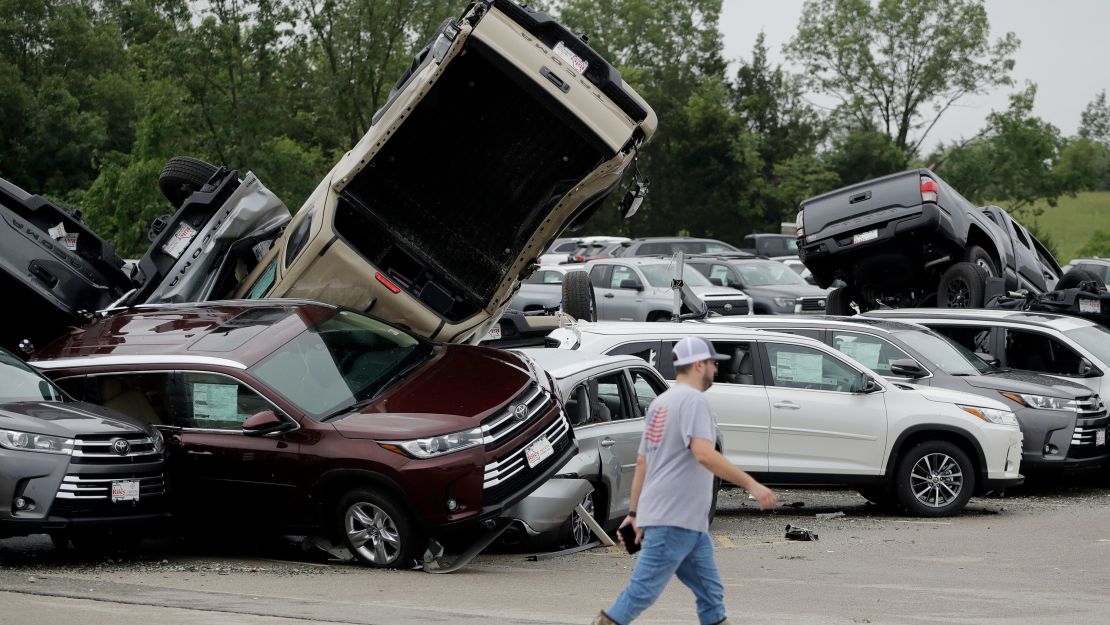 A worker walks past storm-damaged Toyotas on Thursday at a car dealership in Jefferson City.