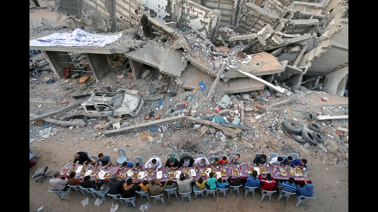 People in Gaza City break their Ramadan fast Saturday, May 18, near a building that was recently destroyed by an Israeli airstrike. 