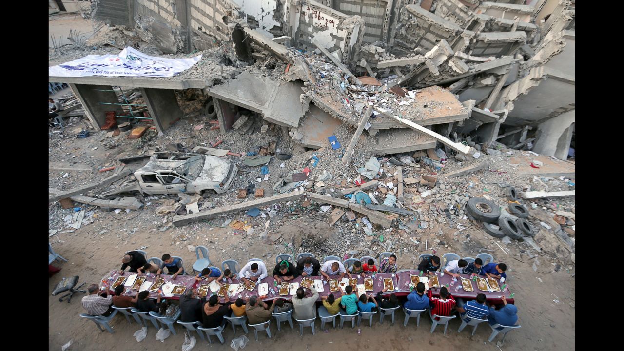 People in Gaza City break their Ramadan fast Saturday, May 18, near a building that was recently destroyed by an Israeli airstrike.