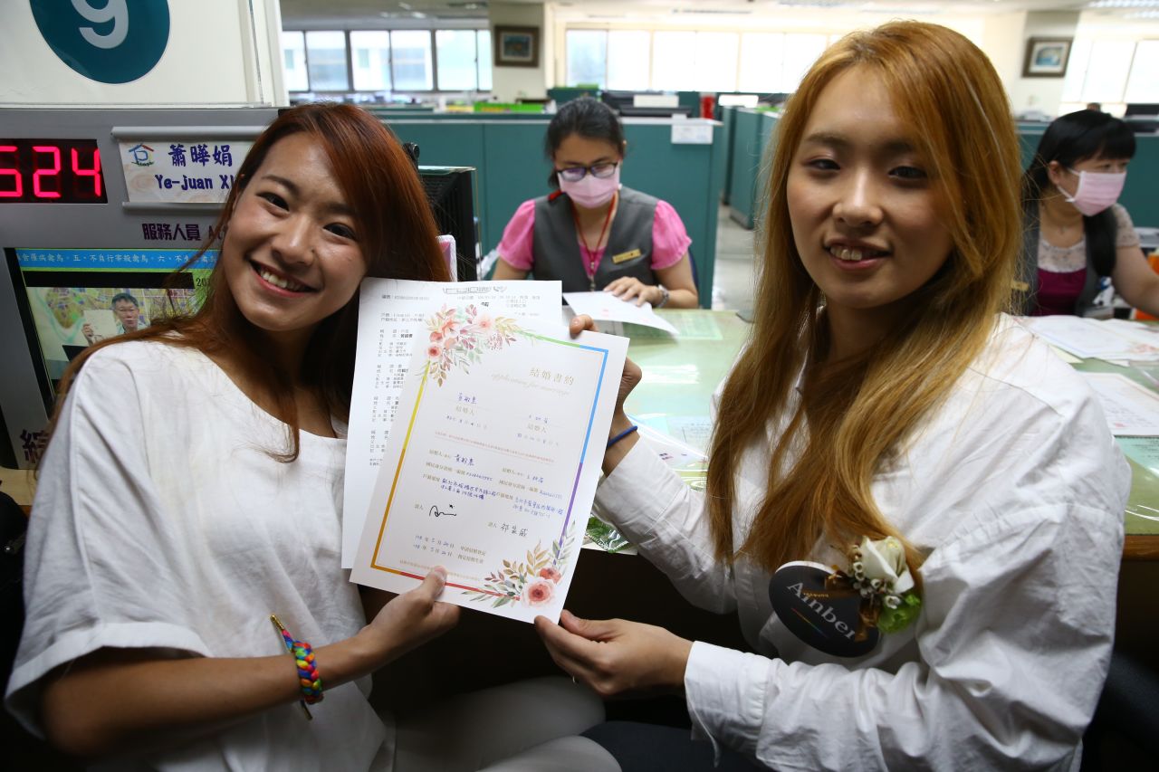 Kristen Huang, left, and her partner Amber Wang, right, hold their marriage certificates.
