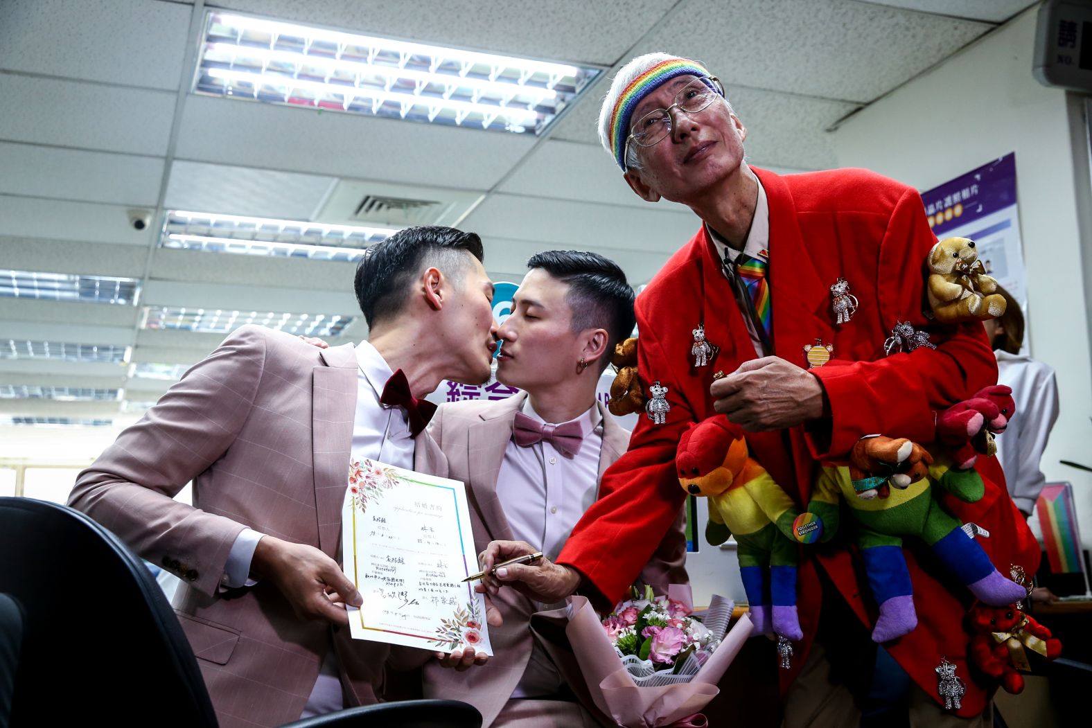Gay rights activist Chi Chia-wei, right, witnessed gay couple Marc Yuan, left, and Shane Lin, center, register their marital status and receive new identification cards.<br />
